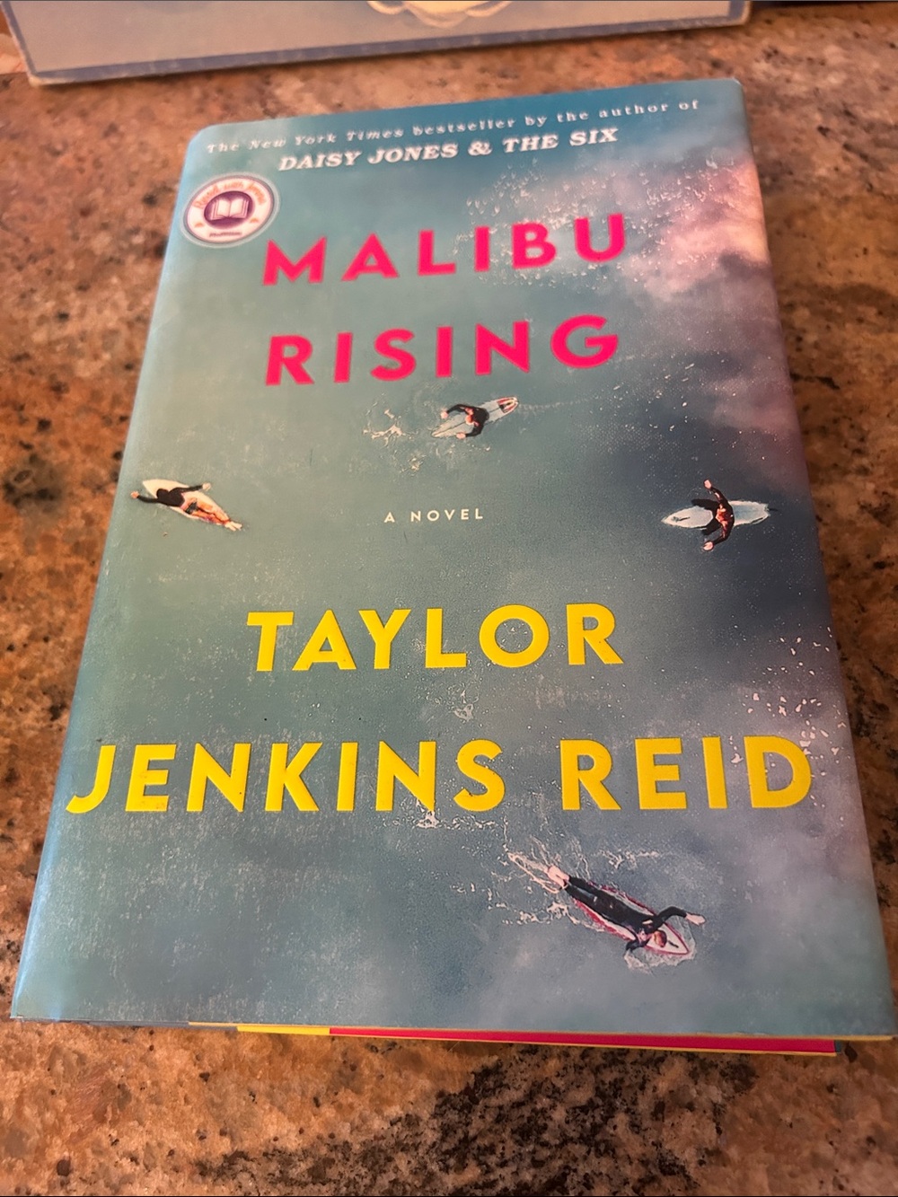 Malibu Rising by Taylor Jenkins Reid - Blue Cover with Yellow & Pink Text